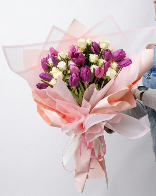 Bouquet of tulips with pink and white ribbons on a light background